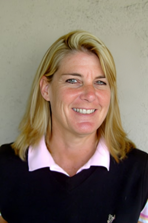 Smiling woman with shoulder-length blonde hair, wearing a black sweater with a pink-collared shirt underneath.